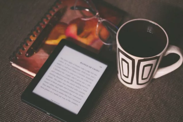 E-book reader, note book  and a cup of coffee. Photo.