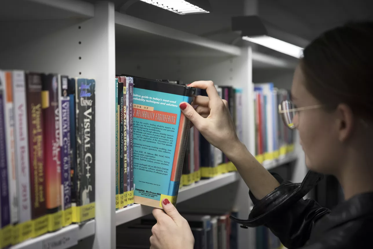 Student tar bok från bokhylla. Foto Johan Bävman